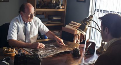 Exhume review photo of two characters at a desk